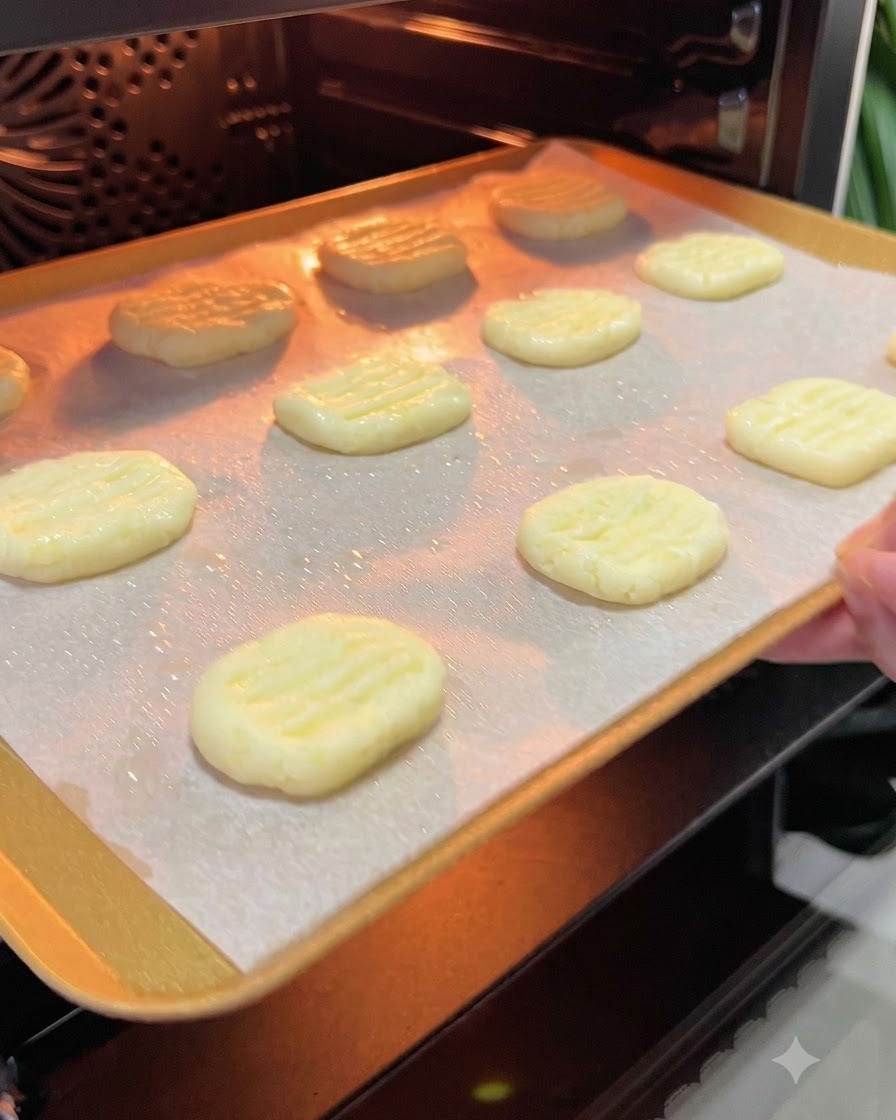 Une plaque de cuisson garnie de galettes de pommes de terre glissée dans lintérieur incandescent dun four préchauffé.