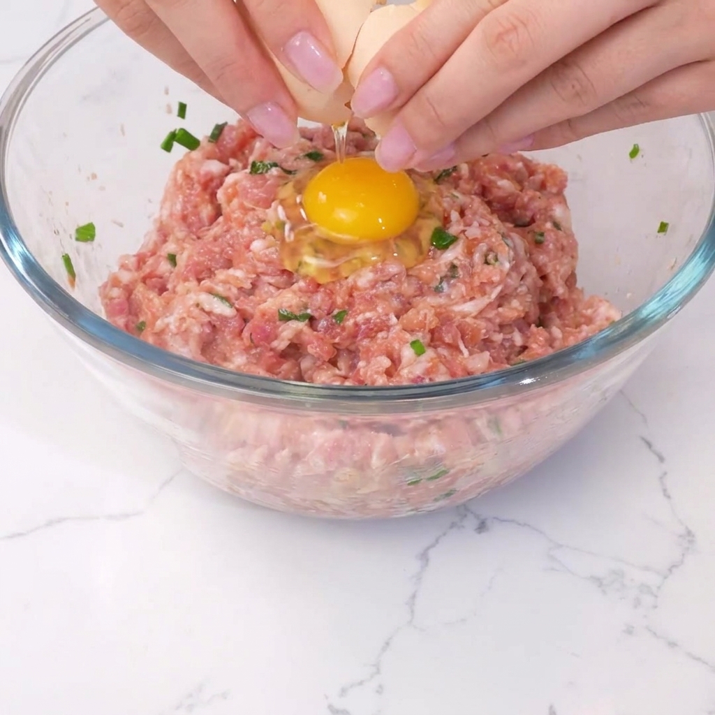 Un œuf cassé au centre du mélange de viande assaisonnée.