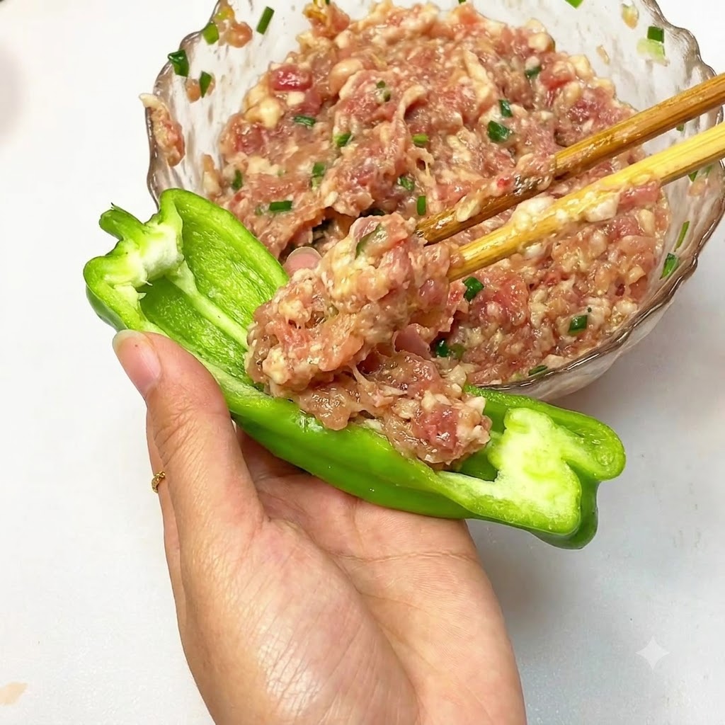 Farce de viande hachée en cours de garnissage dans un demi-poivron vert.