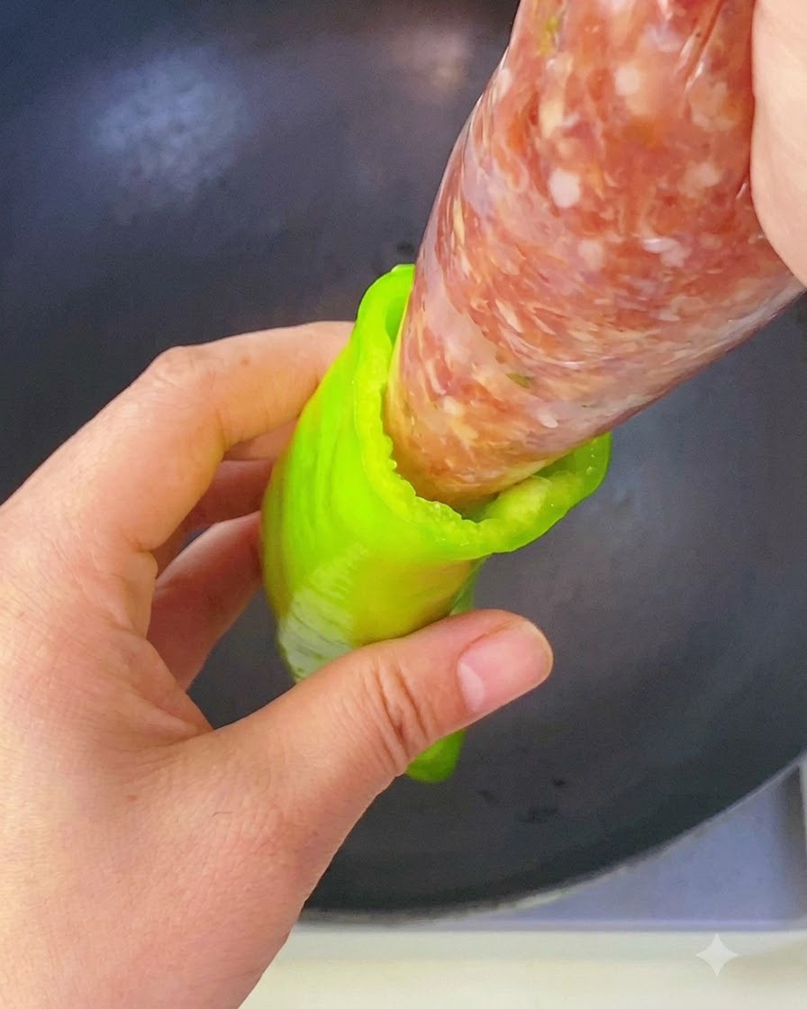 Une main pressant de la farce de viande assaisonnée à partir dune poche à douille directement dans la cavités dun piment vert.