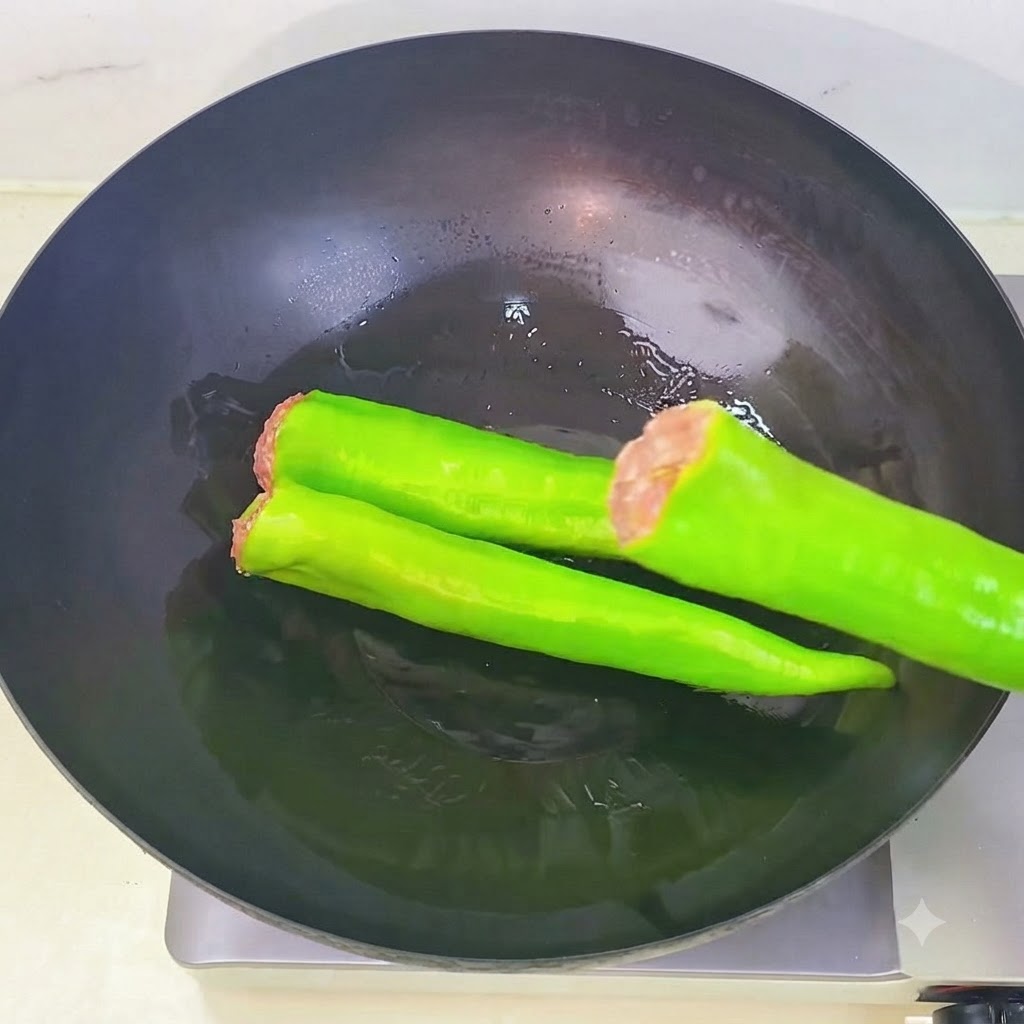 Des piments verts farcis disposés les uns après les autres dans un wok chaud contenant de lhuile.