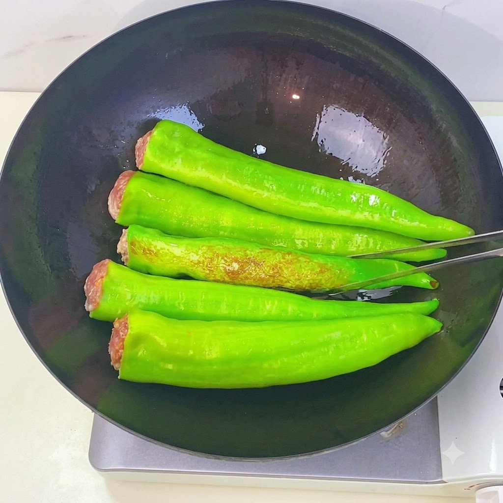 Des piments verts frisant dans un wok et présentant des taches brunes et ridées en peau de tigre pendant quils sont retournés avec des pinces de cuisine.