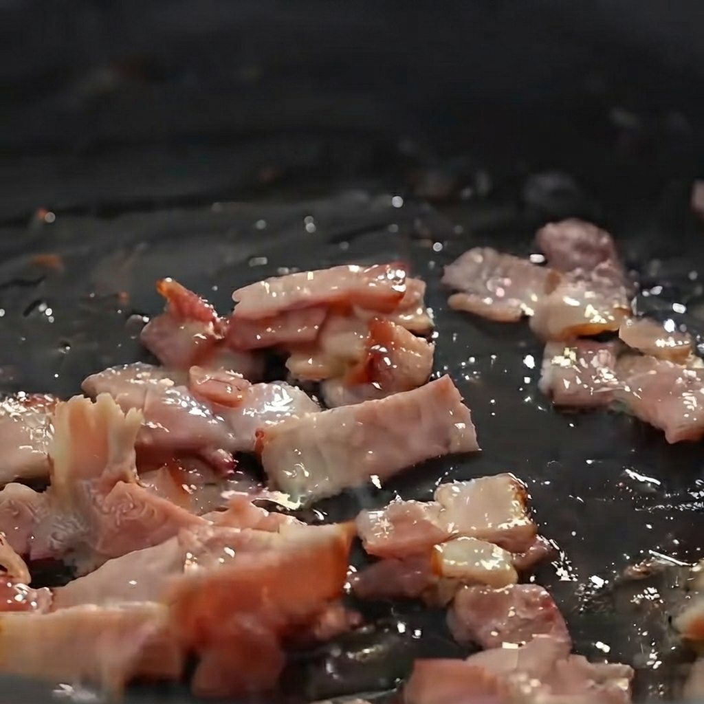 Des pommes de terre, oignons et céleris coupés en dés et sautés avec des morceaux de bacon dans une poêle.
