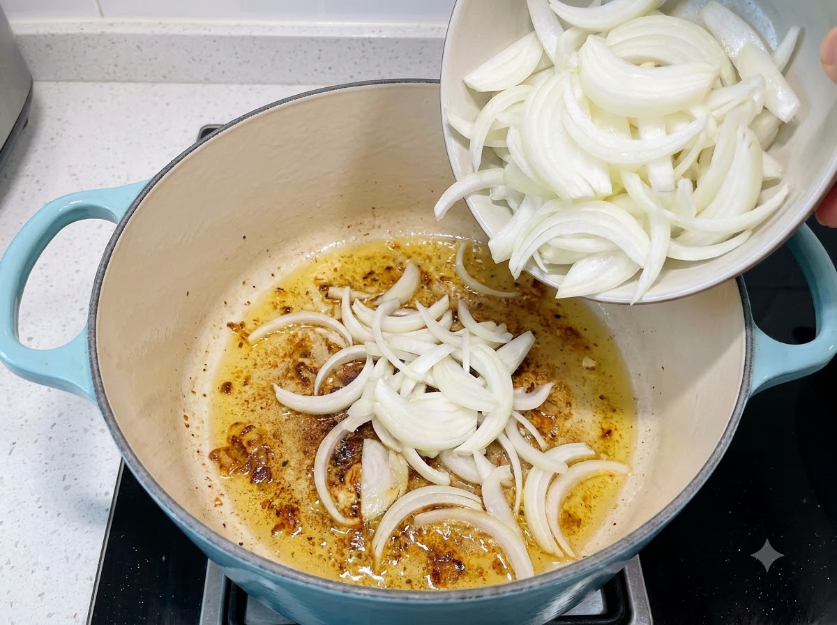 Des oignons tranchés versés dun petit bol dans une casserole contenant de lail et de lhuile en train de suer.
