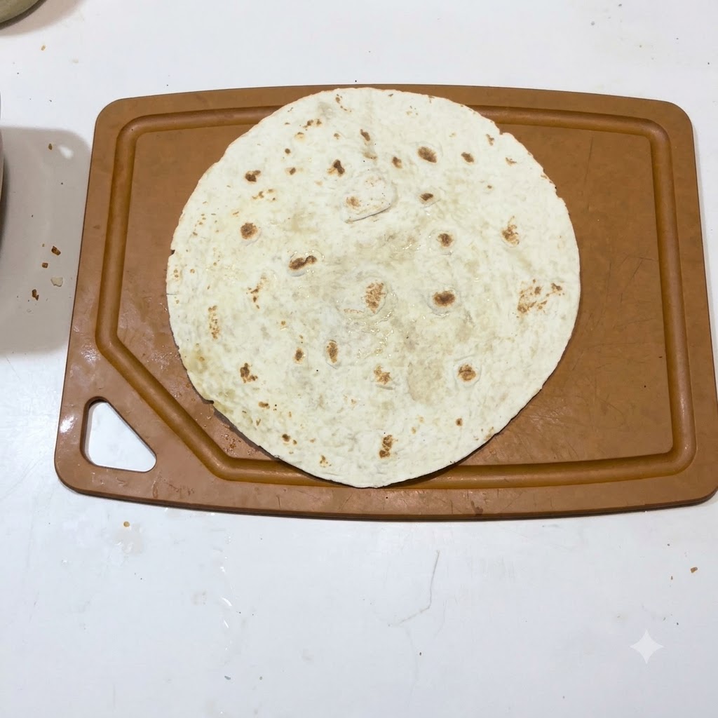 Une seule tortilla chaude posée à plat sur une surface de planche à découper marron.