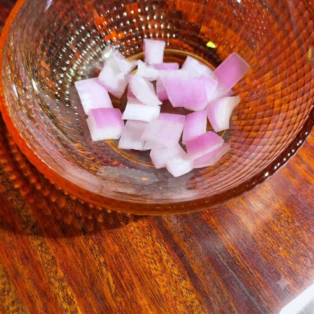 Un bol en verre contenant des morceaux doignon rouge fraîchement coupés en dés, prêts pour la salsa à lavocat.