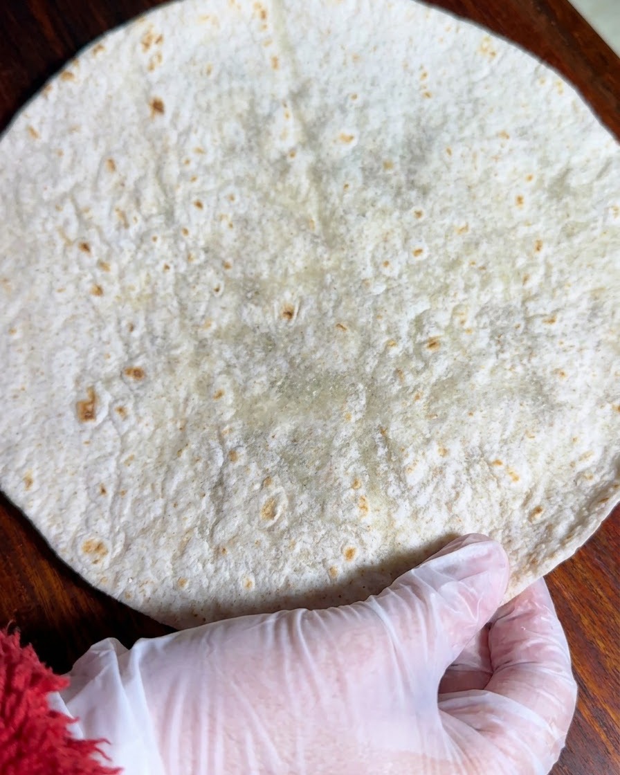 Une tortilla de blé entier posée à plat sur une surface en bois.