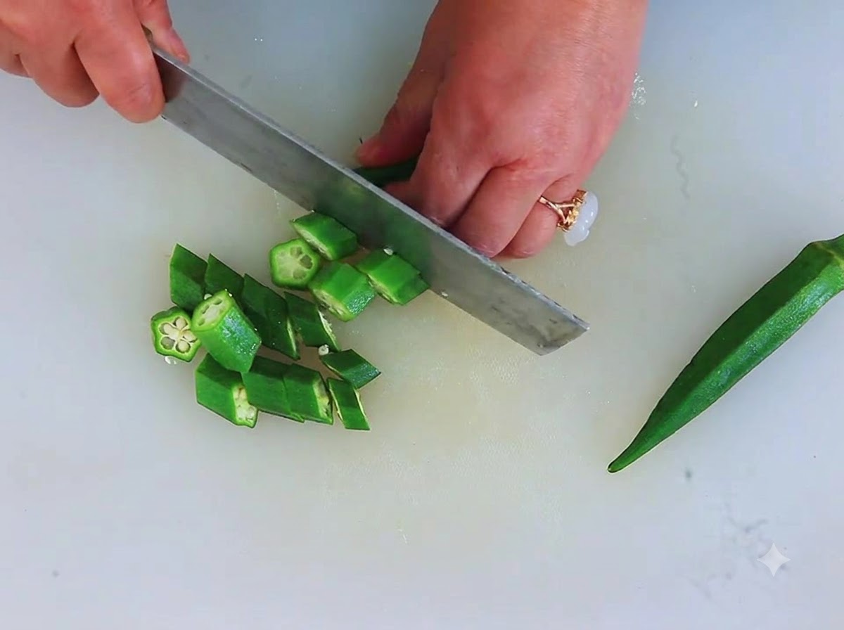 Des gombos verts frais coupés en petits morceaux en forme détoile sur une planche à découper.