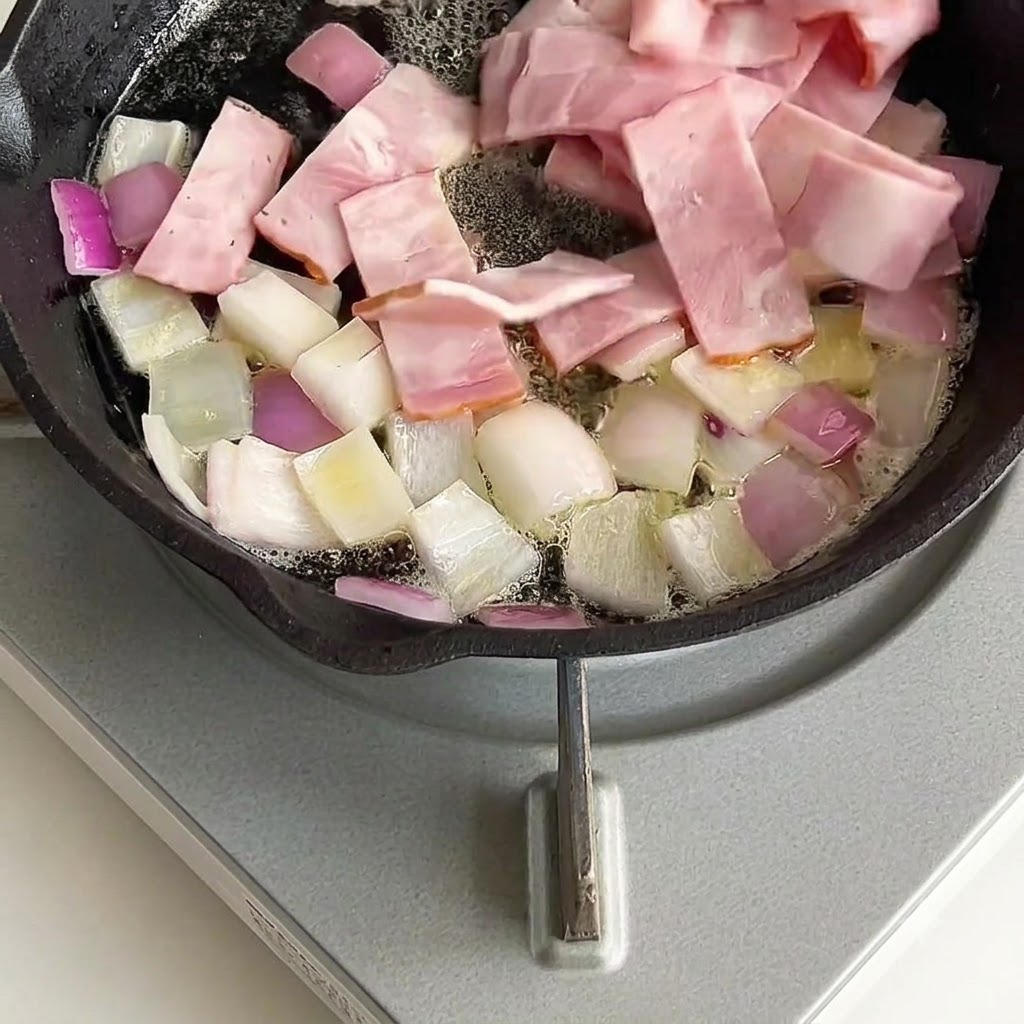 Des morceaux de bacon mélangés et sautés avec des oignons dans la poêle.