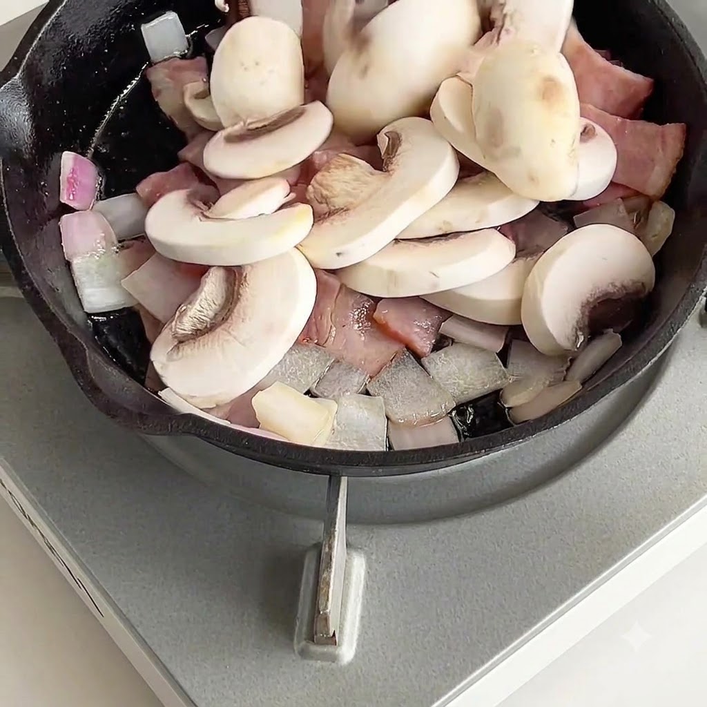 Des champignons blancs tranchés placés dans une poêle avec des morceaux de bacon et doignon.