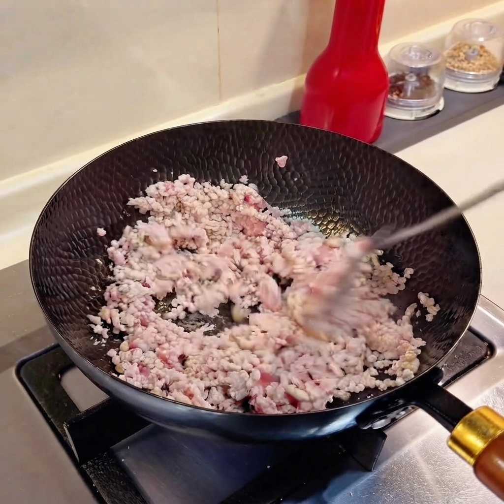 Ciboulette hachée et ail émincé mélangés avec de la viande hachée dans un wok.