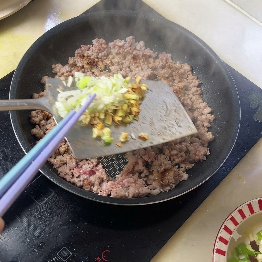Oignons verts et gingembre hachés ajoutés au porc haché cuit dans une poêle.