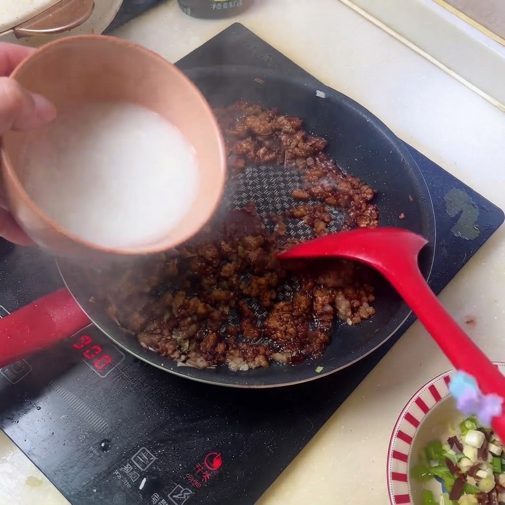 De leau damidon blanche versée dun bol dans la poêle contenant la sauce de viande hachée foncée.