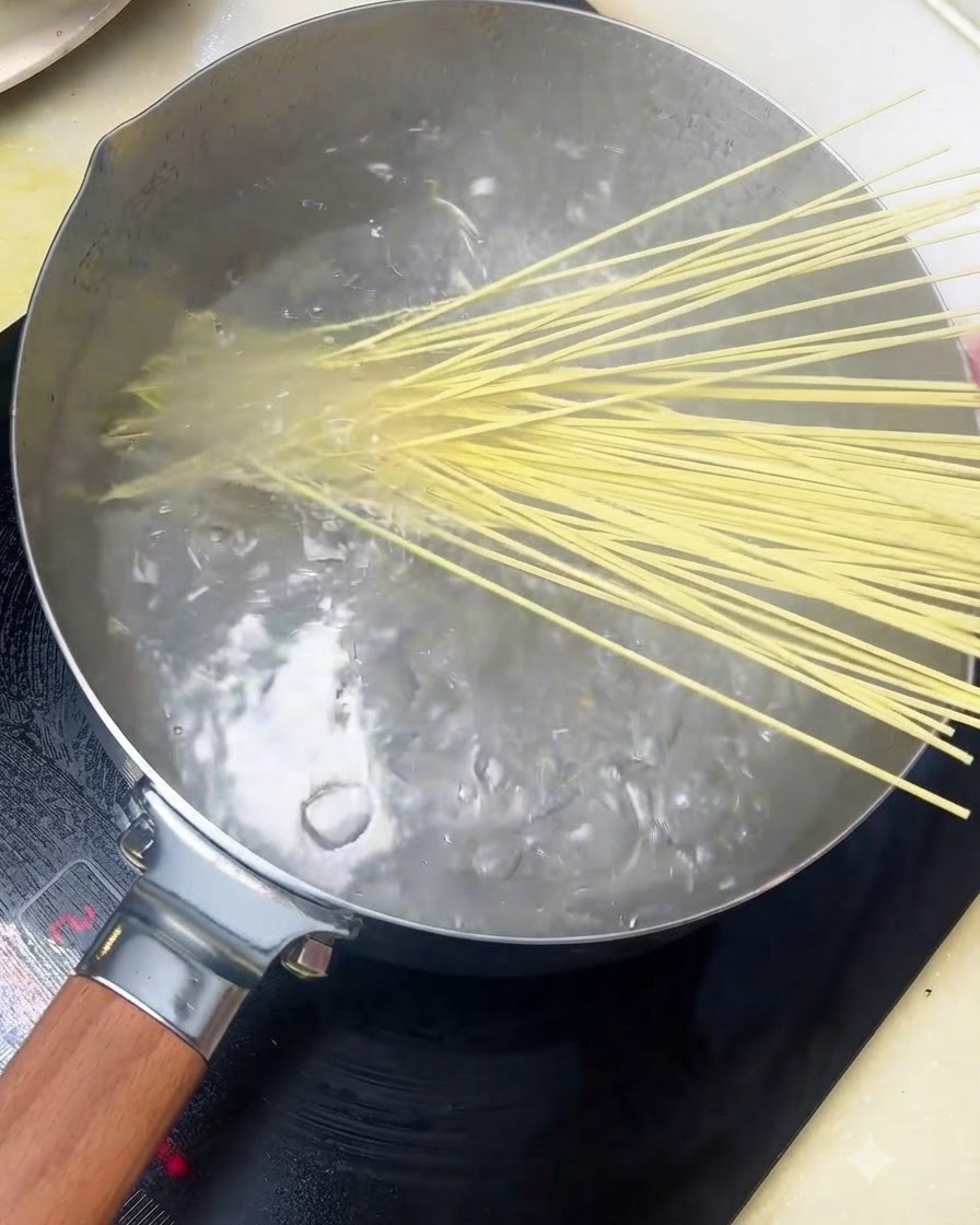 Des nouilles alcalines ajoutées dans une casserole deau bouillante.