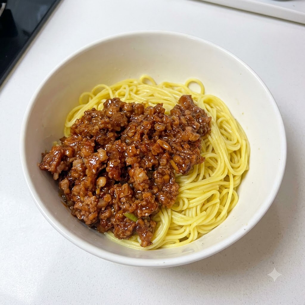 Un bol contenant des nouilles et de la sauce de viande hachée garni doignons verts fraîchement hachés.
