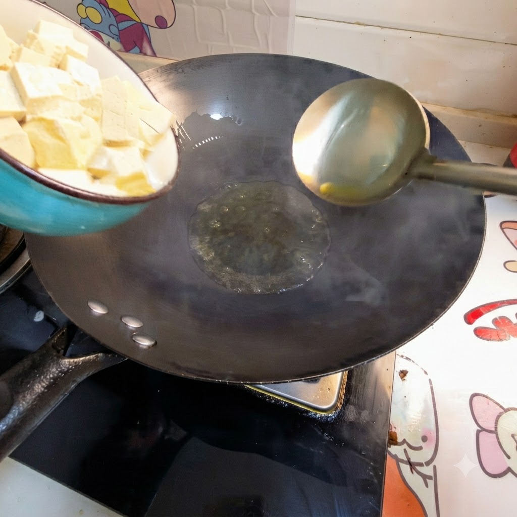 Des cubes de tofu sont versés dun bol dans lhuile chaude dun wok.