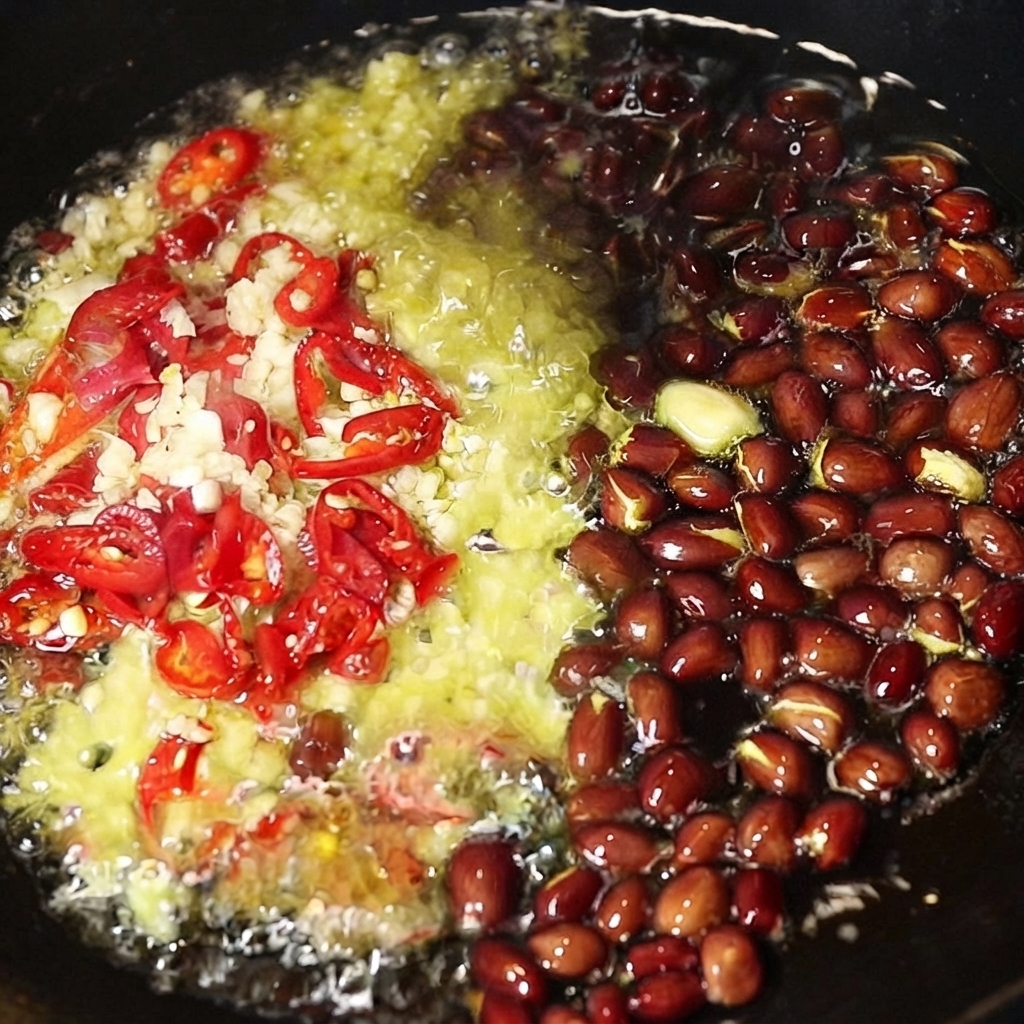 Ail haché, piments rouges tranchés et cacahuètes entières grésillant dans de lhuile chaude à lintérieur dun wok.