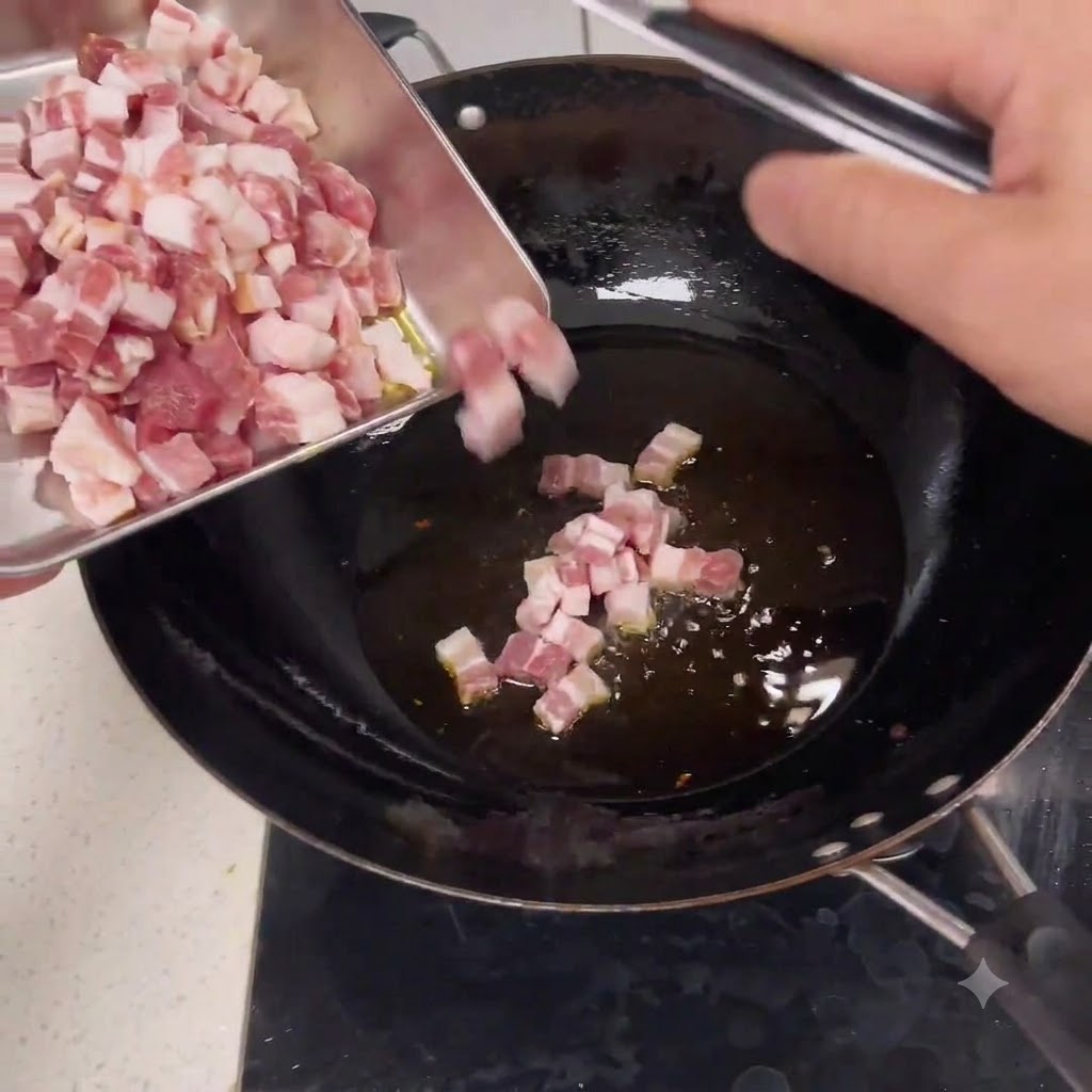 Morceaux de porc cru en dés glissant dun plateau en métal dans un wok avec de lhuile chaude.
