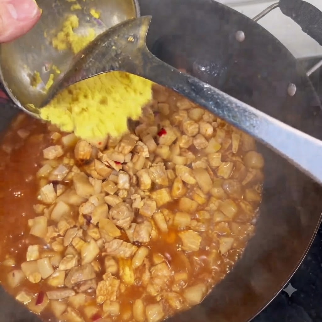 Gingembre haché gratté dune louche dans un wok rempli de viande et de sauce frémissante.