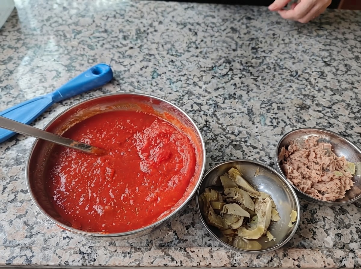 Quatre bols en acier remplis dingrédients à pizza disposés sur une surface en marbre.