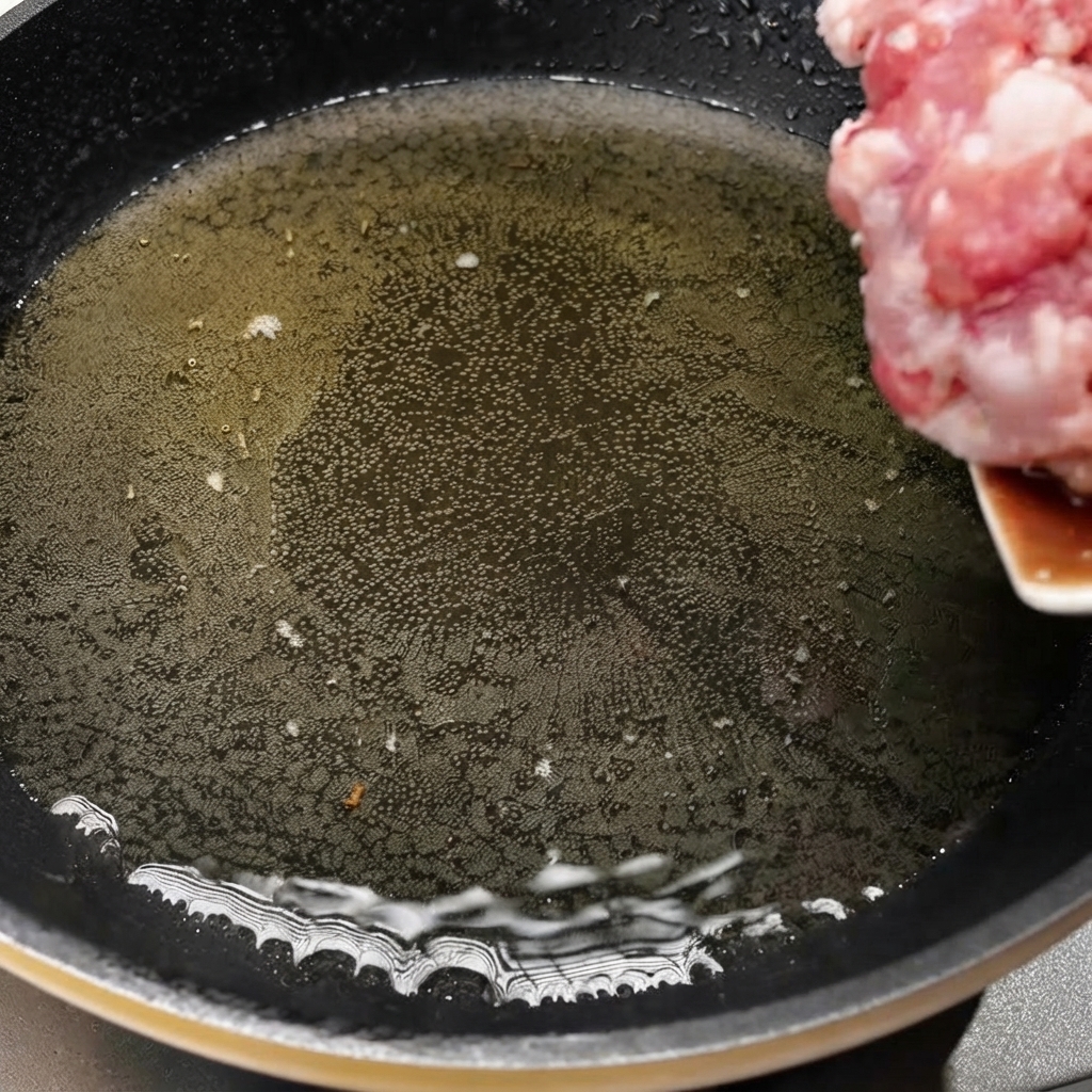 Porc haché transféré dans une poêle chaude avec de lhuile pour commencer la cuisson.