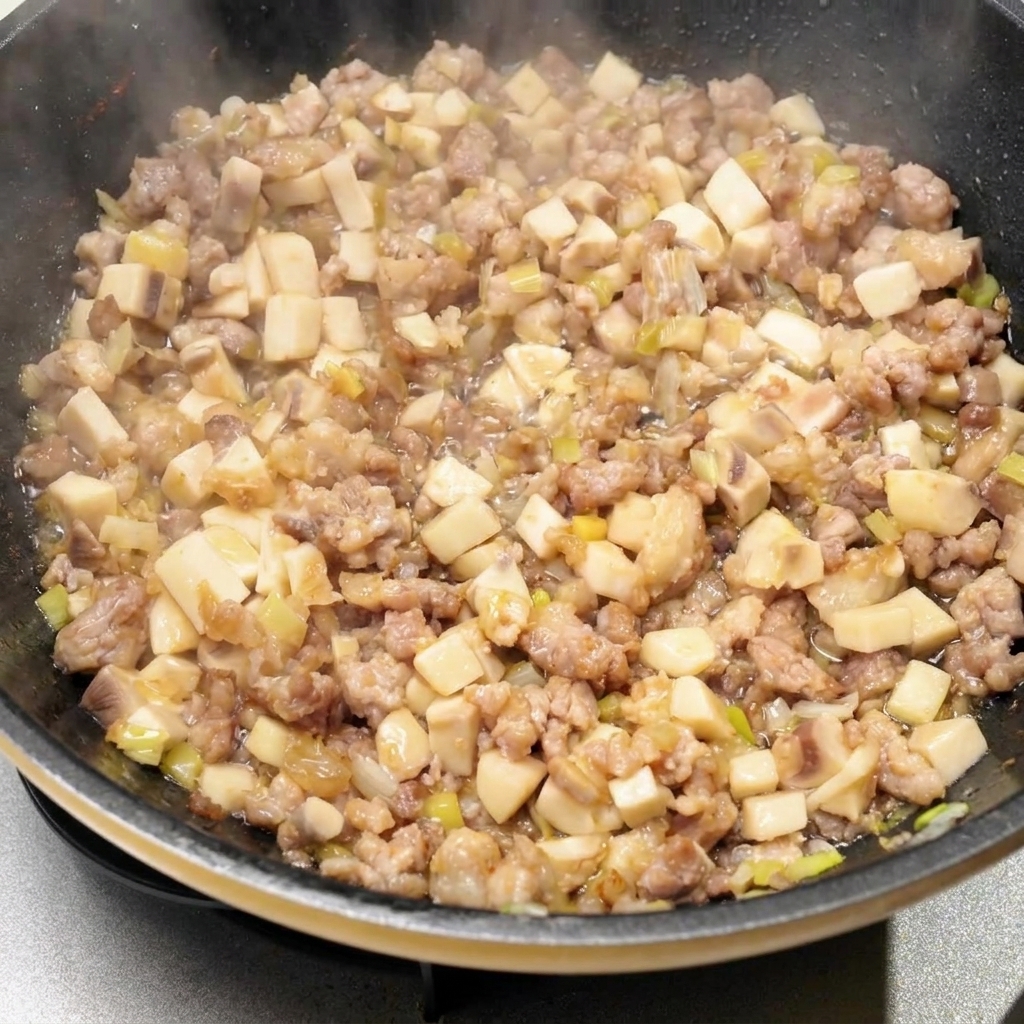 Divers assaisonnements liquides et sauces versés dans la poêle avec le mélange de viande et de champignons.