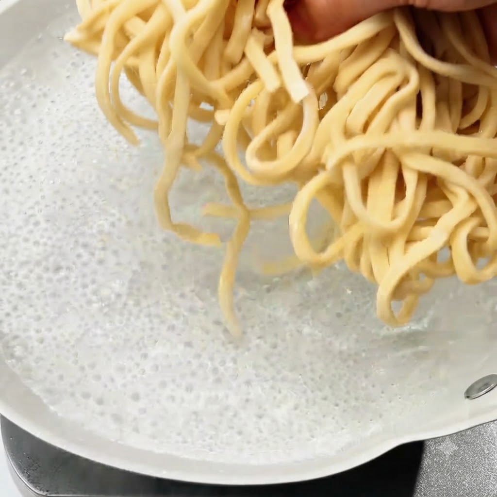 Nouilles fraîches plongées dans une casserole deau bouillante.