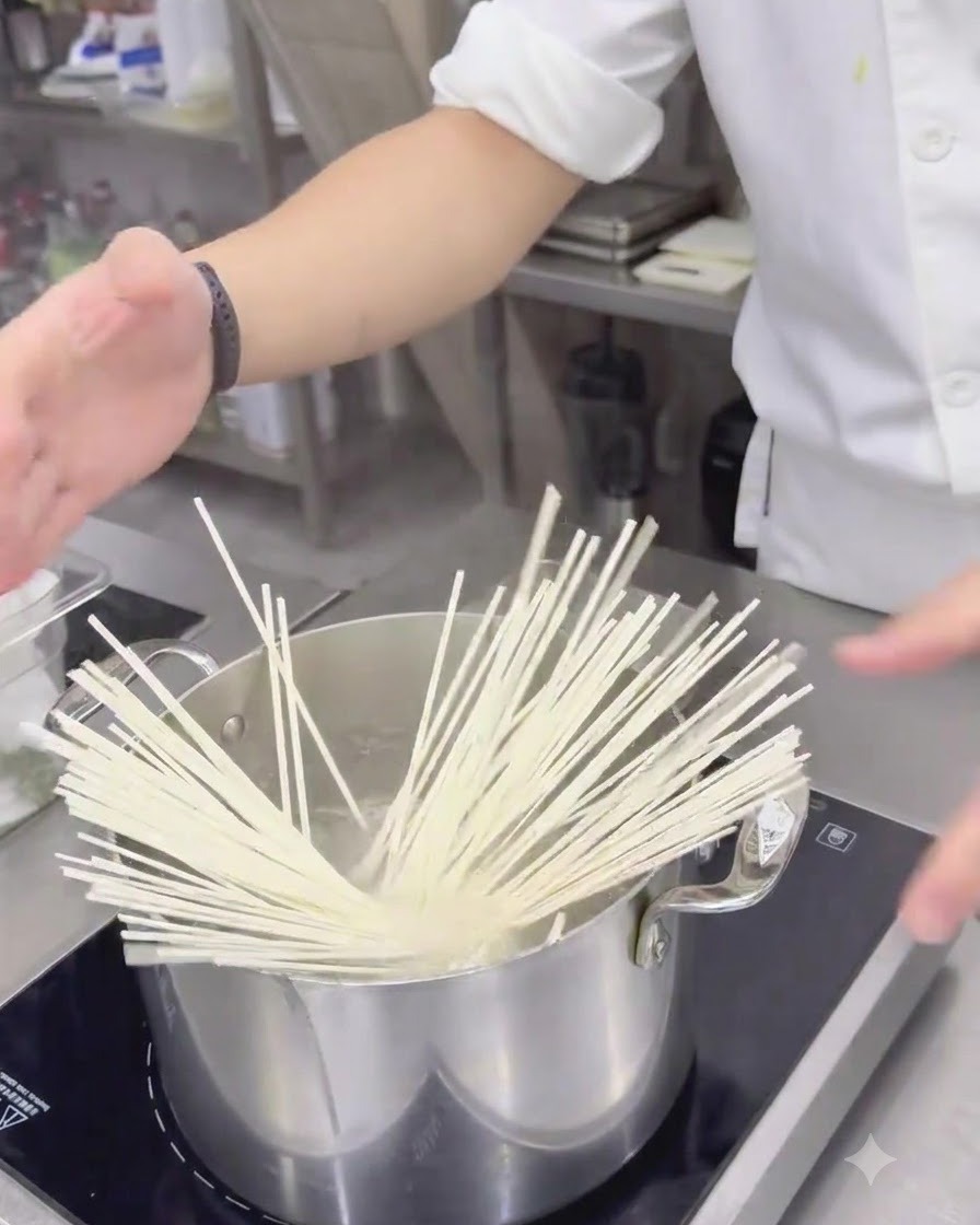 Nouilles udon blanches séchées plongées dans une casserole en acier inoxydable remplie deau bouillante.