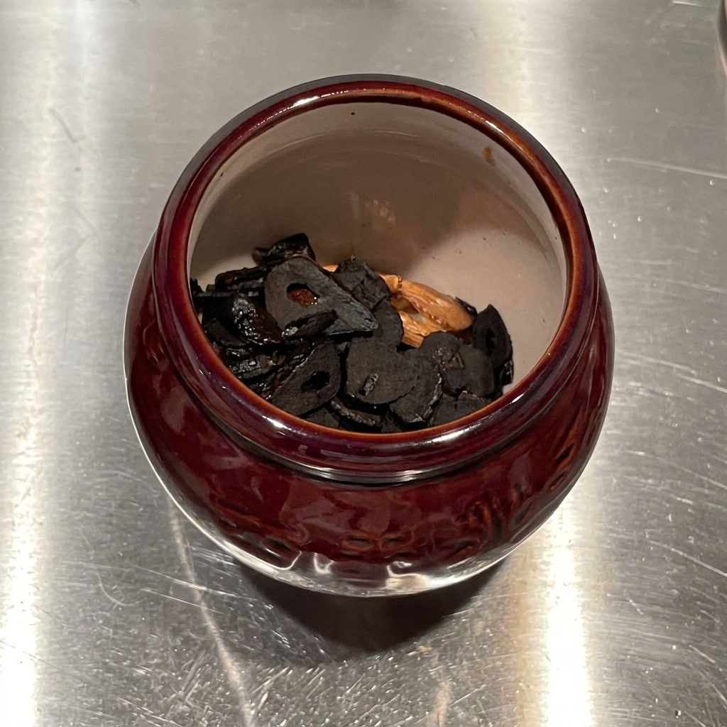 Huile infusée à lail versée du dessus dans un mortier en céramique rempli de chips dail frit.