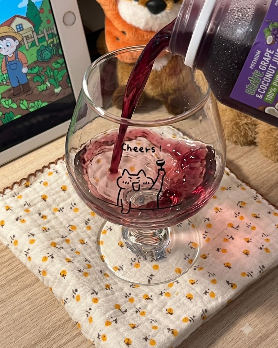 Jus de raisin violet foncé versé dune brique dans un verre transparent sur pied orné dun design de chat cartoon.
