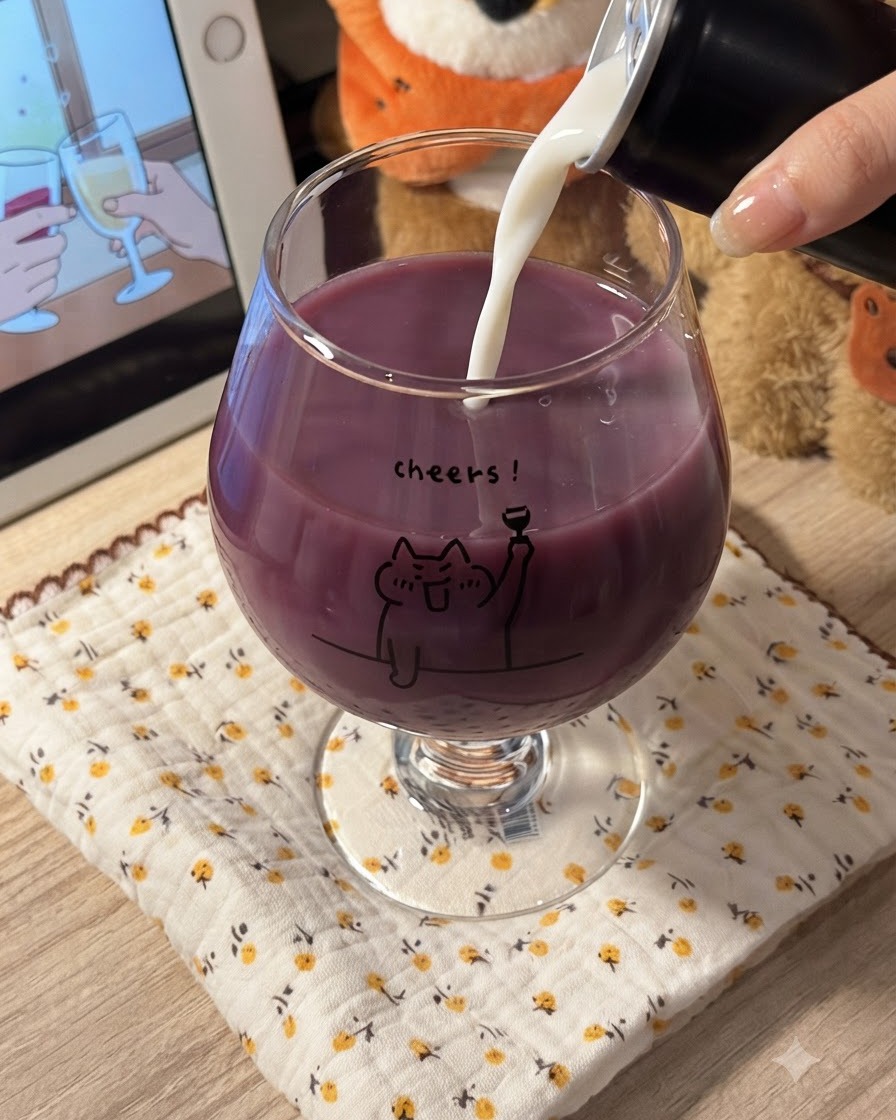 Du lait blanc versé dans un verre rempli de jus de raisin violet, créant un mélange violet crémeux.