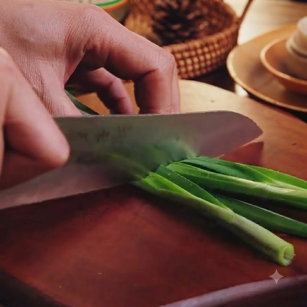 Découpe de ciboulette verte en petits morceaux sur une planche à découper en bois avec un couteau de cuisine.
