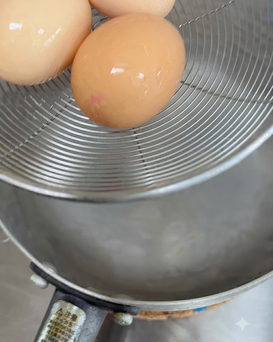 Trois œufs crus reposant dans un panier en maille au-dessus de leau chaude.