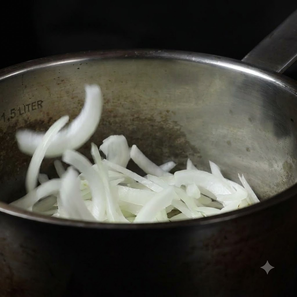 Des oignons tranchés en train dêtre versés dans une casserole en acier inoxydable.