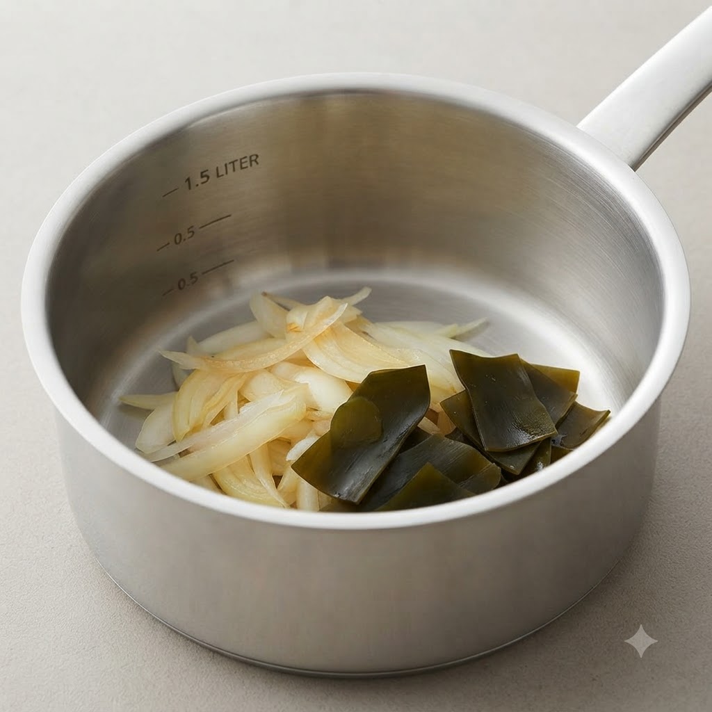 Une casserole contenant des oignons tendres cuits à côté dun nœud de kombu plié.