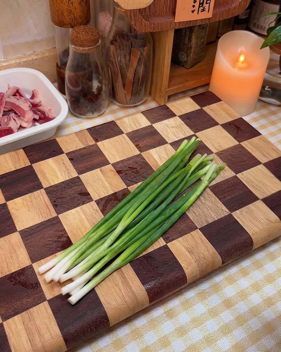 Des oignons nouveaux frais disposés et prêts à être hachés sur une planche en bois.