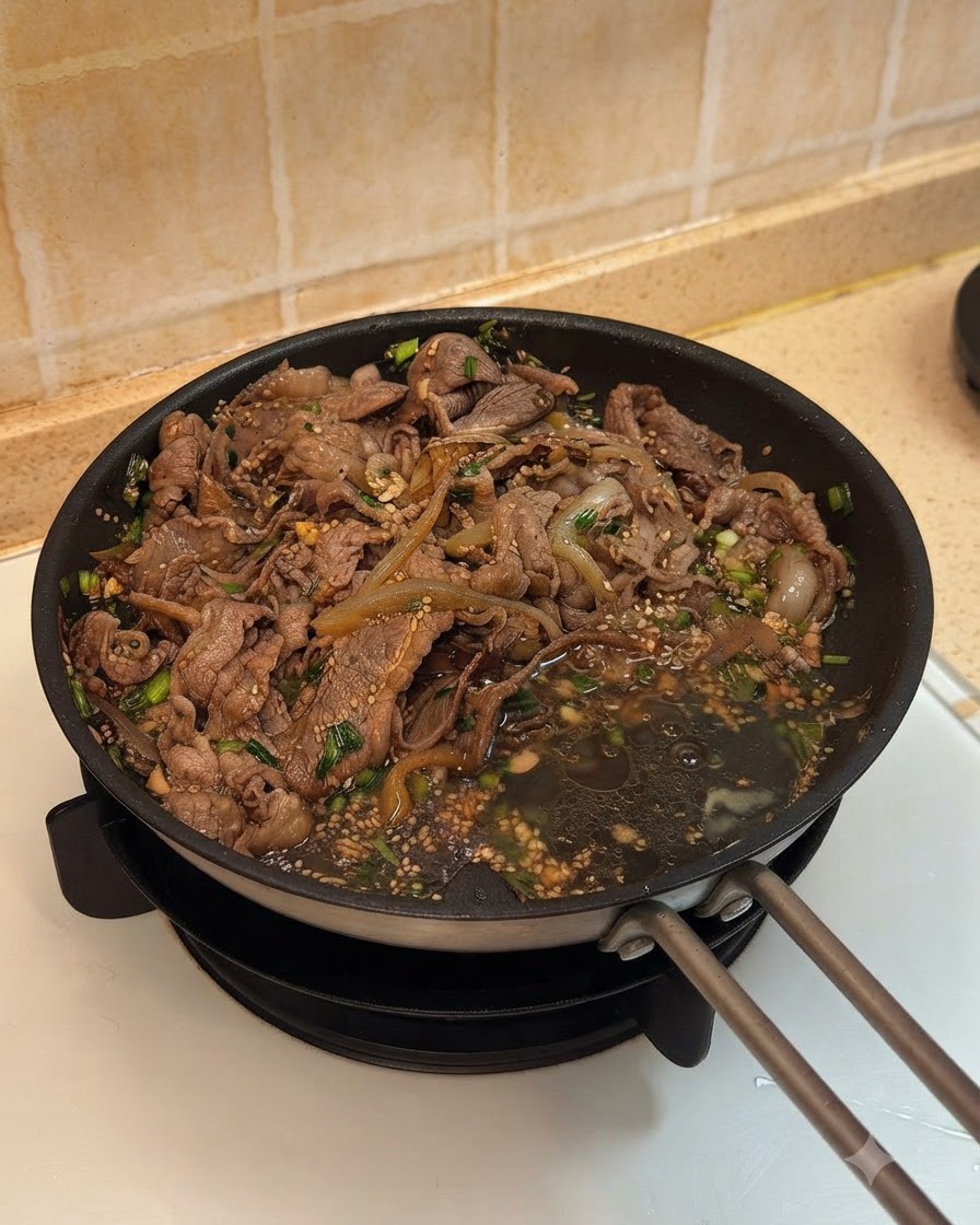 Deux œufs cassés dans la poêle à côté du bœuf cuit et des oignons en sauce.