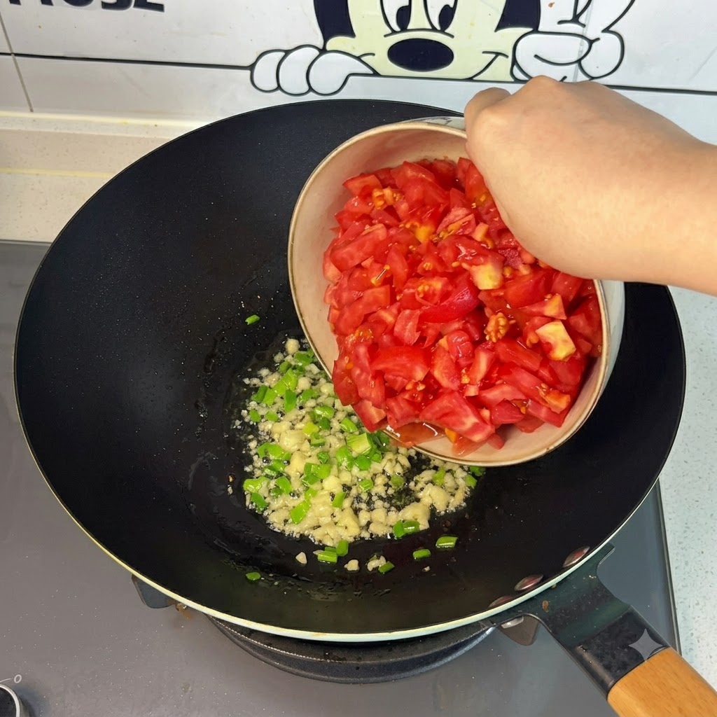 Des tomates rouges fraîchement coupées versées dun bol dans le wok.