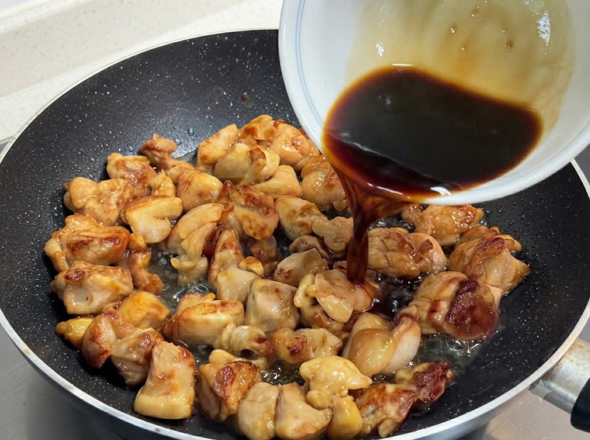 Un mélange de sauce sombre et savoureuse versé dun bol blanc sur des morceaux de poulet sautés dorés dans une poêle.