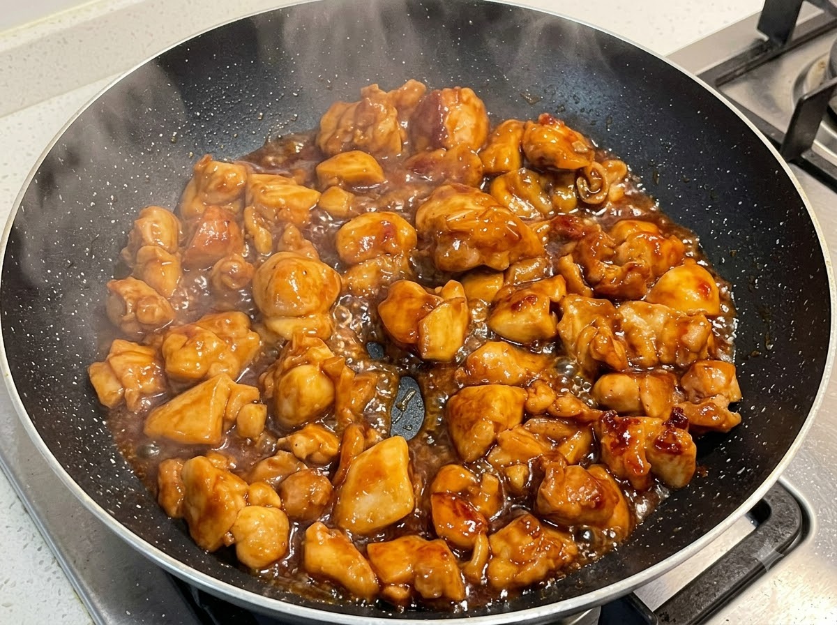 Poulet mijotant dans une sauce épaisse à lintérieur dune poêle à frire.