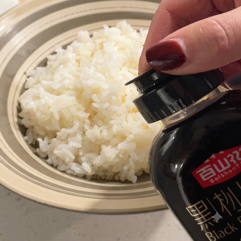 Sauce à la truffe noire versée depuis une bouteille sur un bol de riz blanc cuit à la vapeur.