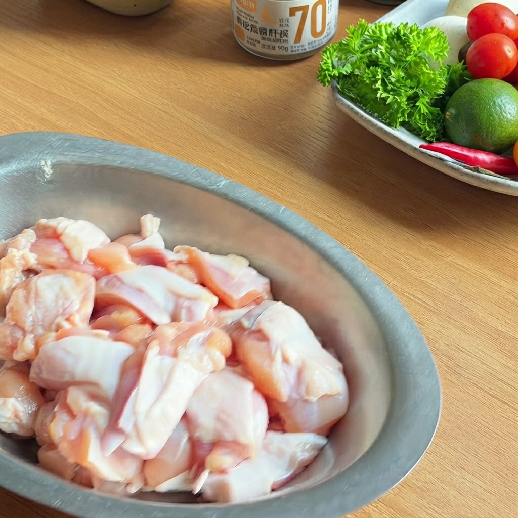 Un bol en métal rempli de morceaux de poulet crus assaisonnés avec de la sauce soja foncée, de la sauce huître et du poivre noir.