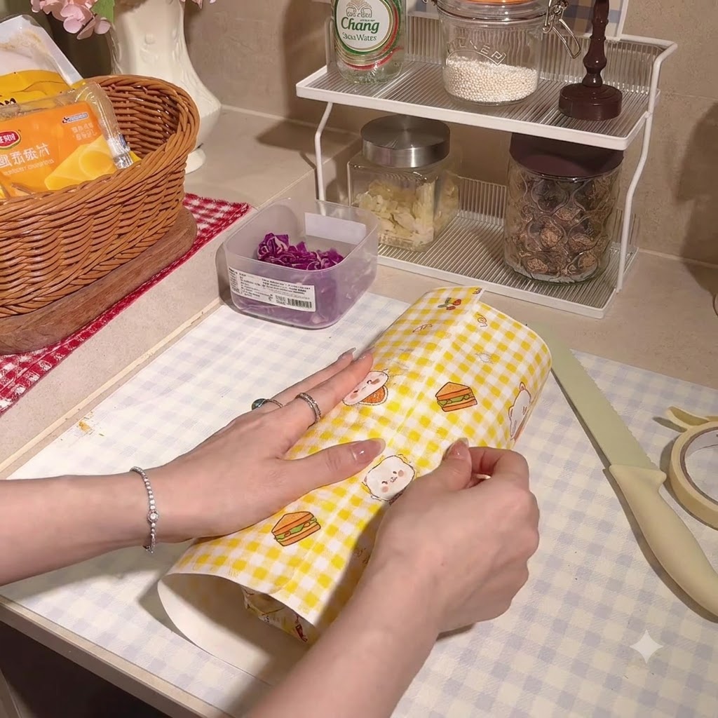 Sandwich épais soigneusement enveloppé et serré dans du papier sulfurisé quadrillé.