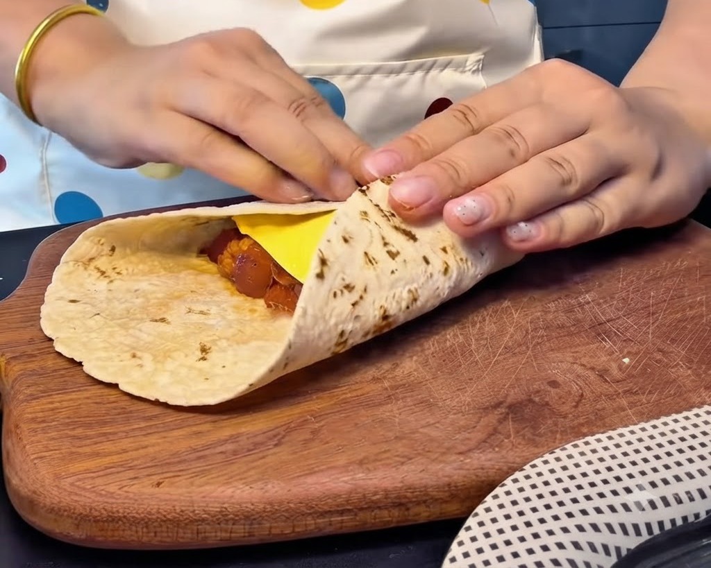 Mains pliant fermement les bords dune galette sur une tranche de fromage et sa garniture pour créer un chausson carré bien fermé.