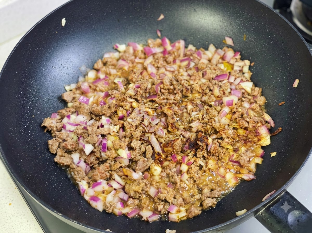 Pâte de curry et épices sautées avec le mélange de bœuf et doignon dans la poêle.