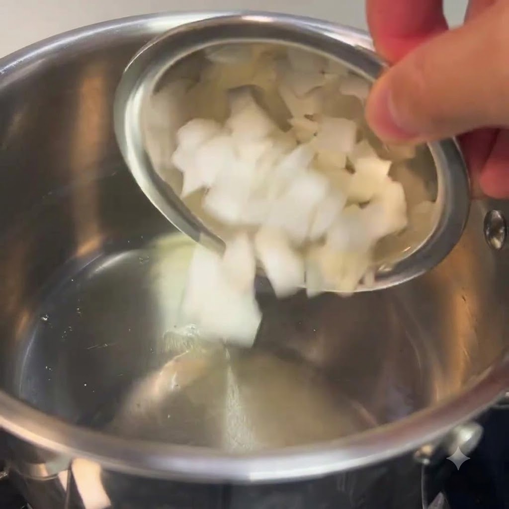 Des oignons blancs hachés versés dun petit bol dans une casserole en acier inoxydable.