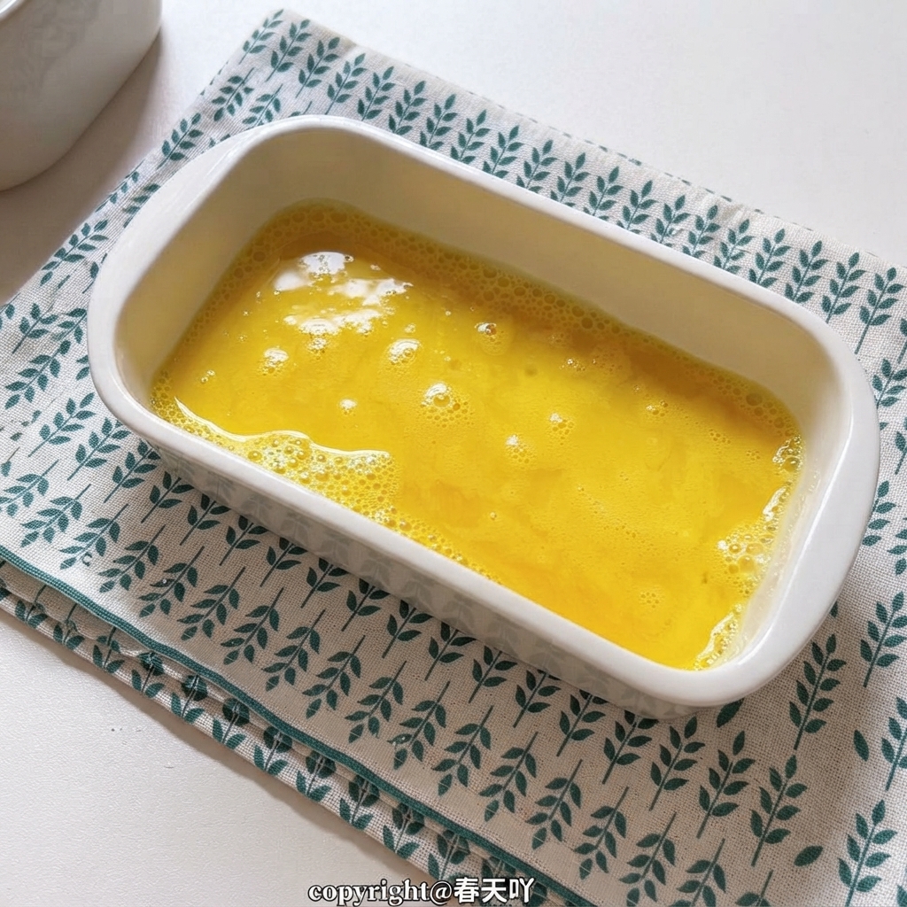 Un plat en céramique blanche rempli dœufs battus jaune doré.