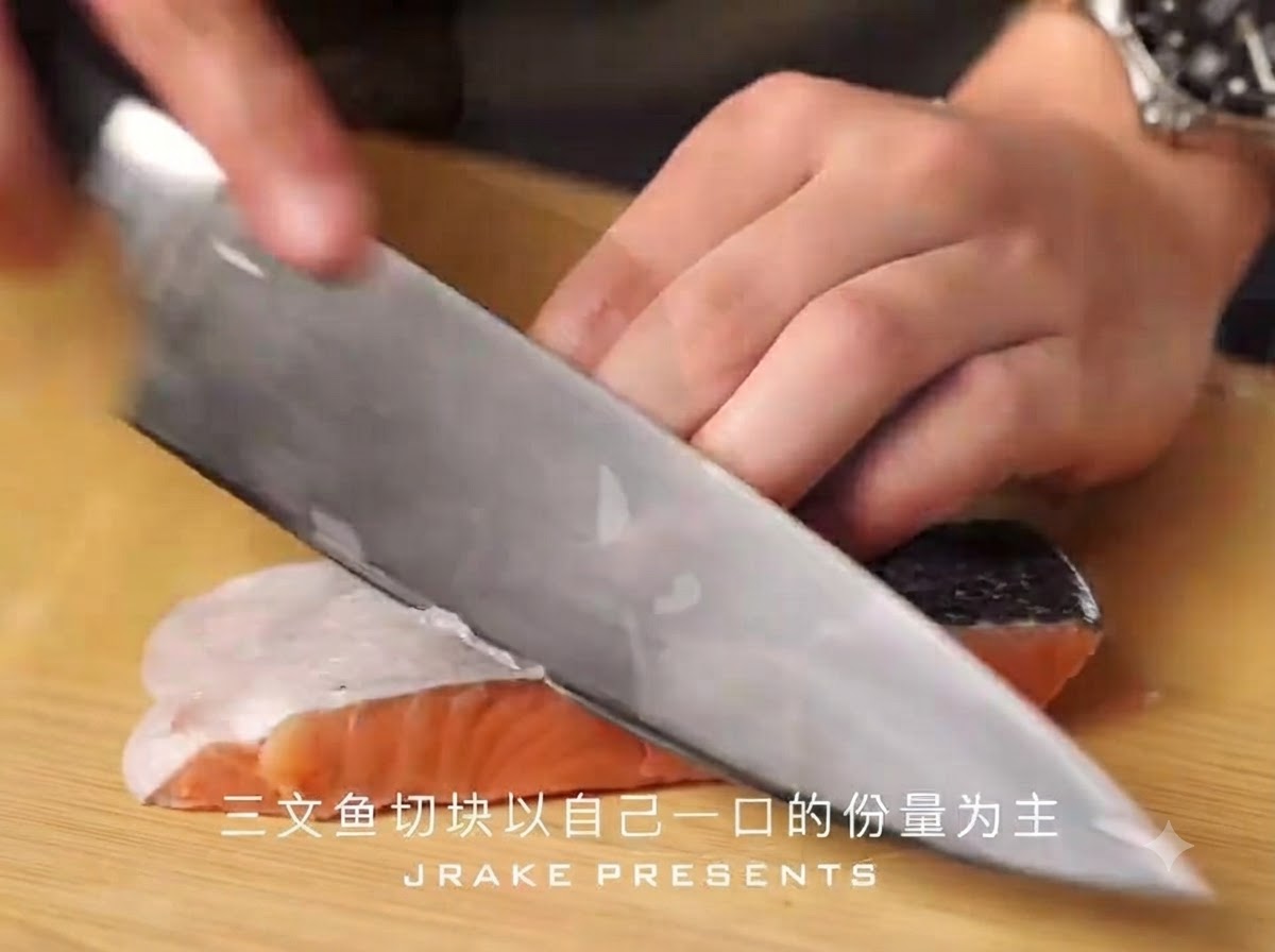 Un couteau de chef tranchant découpe un filet de saumon avec la peau en morceaux de taille bouchée sur une planche à découper en bois.