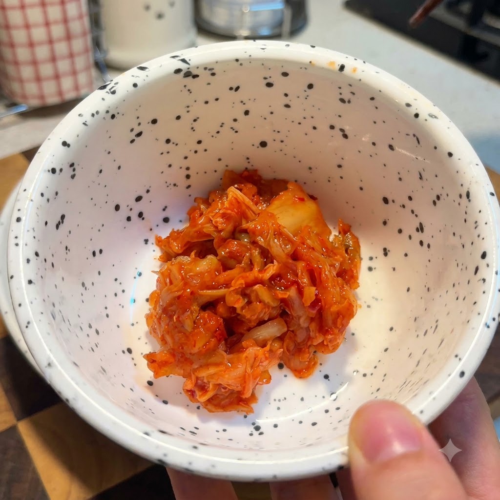 Un bol blanc moucheté rempli dune portion de kimchi haché rouge vif.