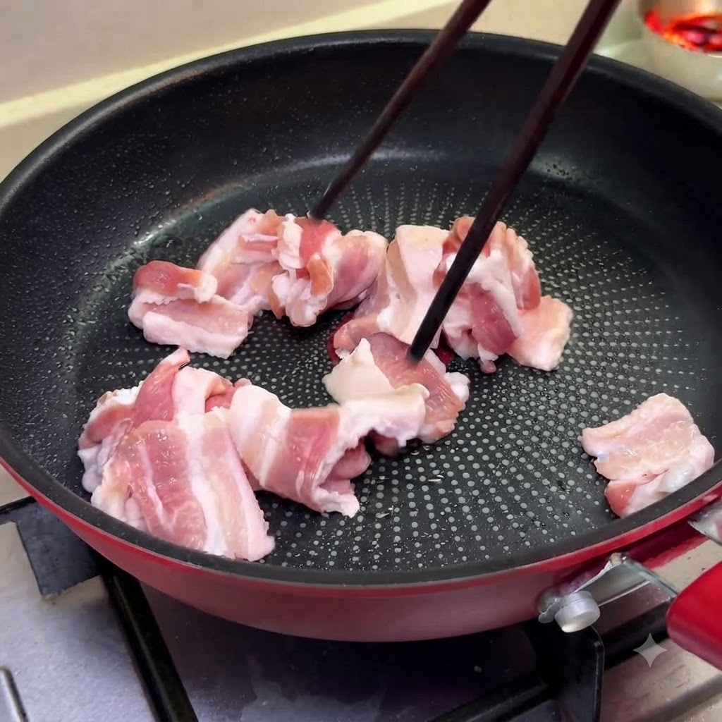 De fines tranches de poitrine de porc cuisant dans une poêle à feu moyen à laide de baguettes.